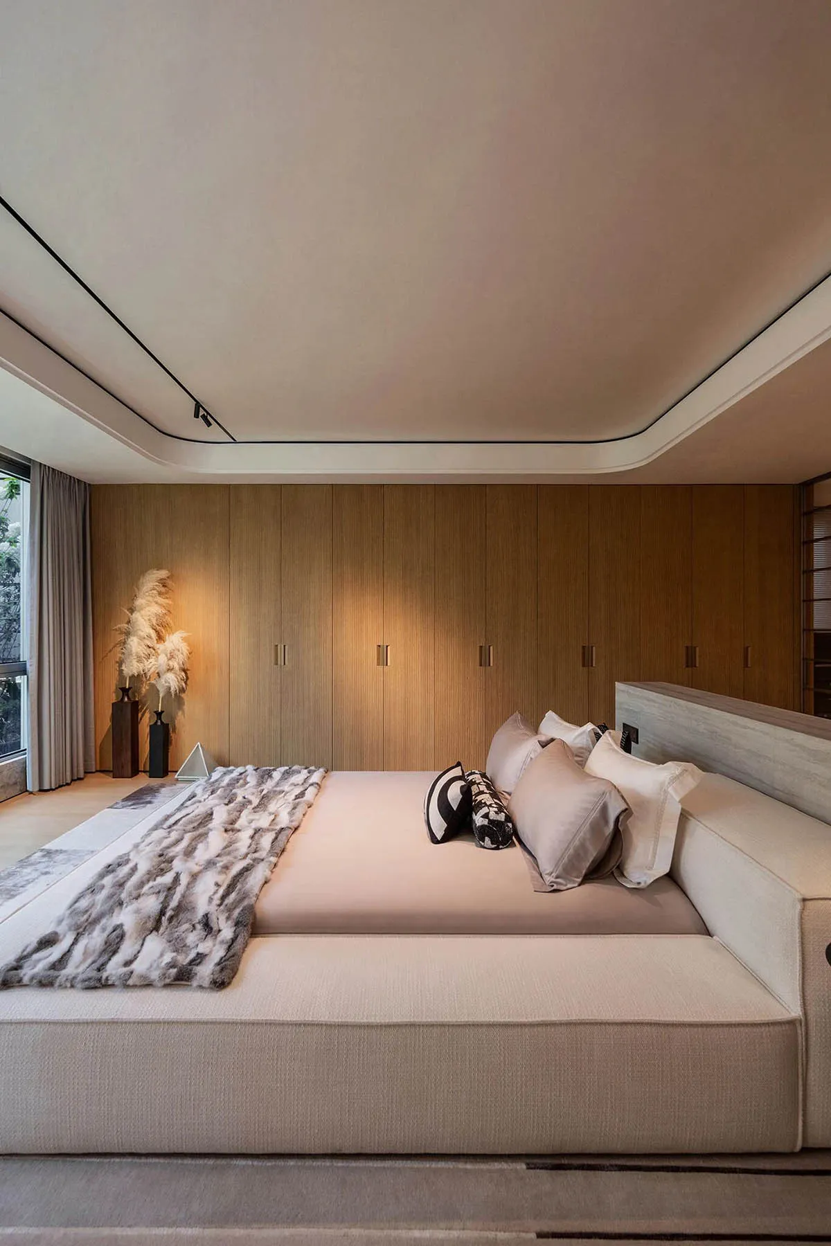 A well-furnished bedroom with a large bed, two couches, a chair, and a potted plant, creating a cozy atmosphere