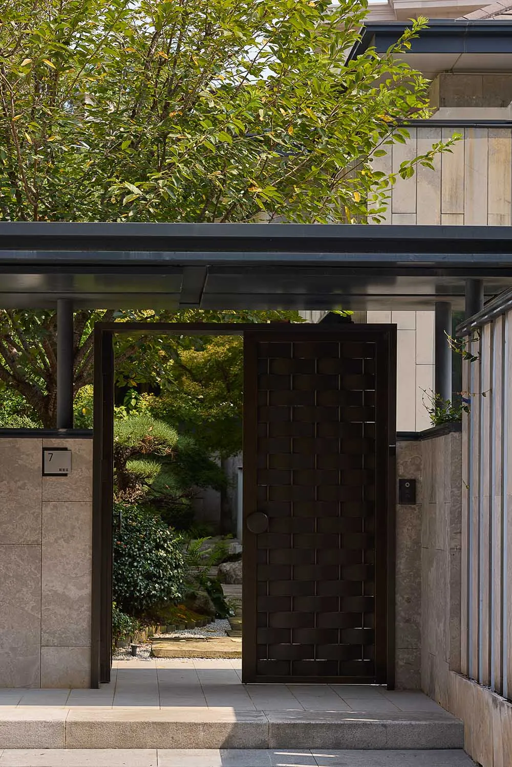 A serene entrance with a wooden door, surrounded by trees and bushes, creating a peaceful atmosphere
