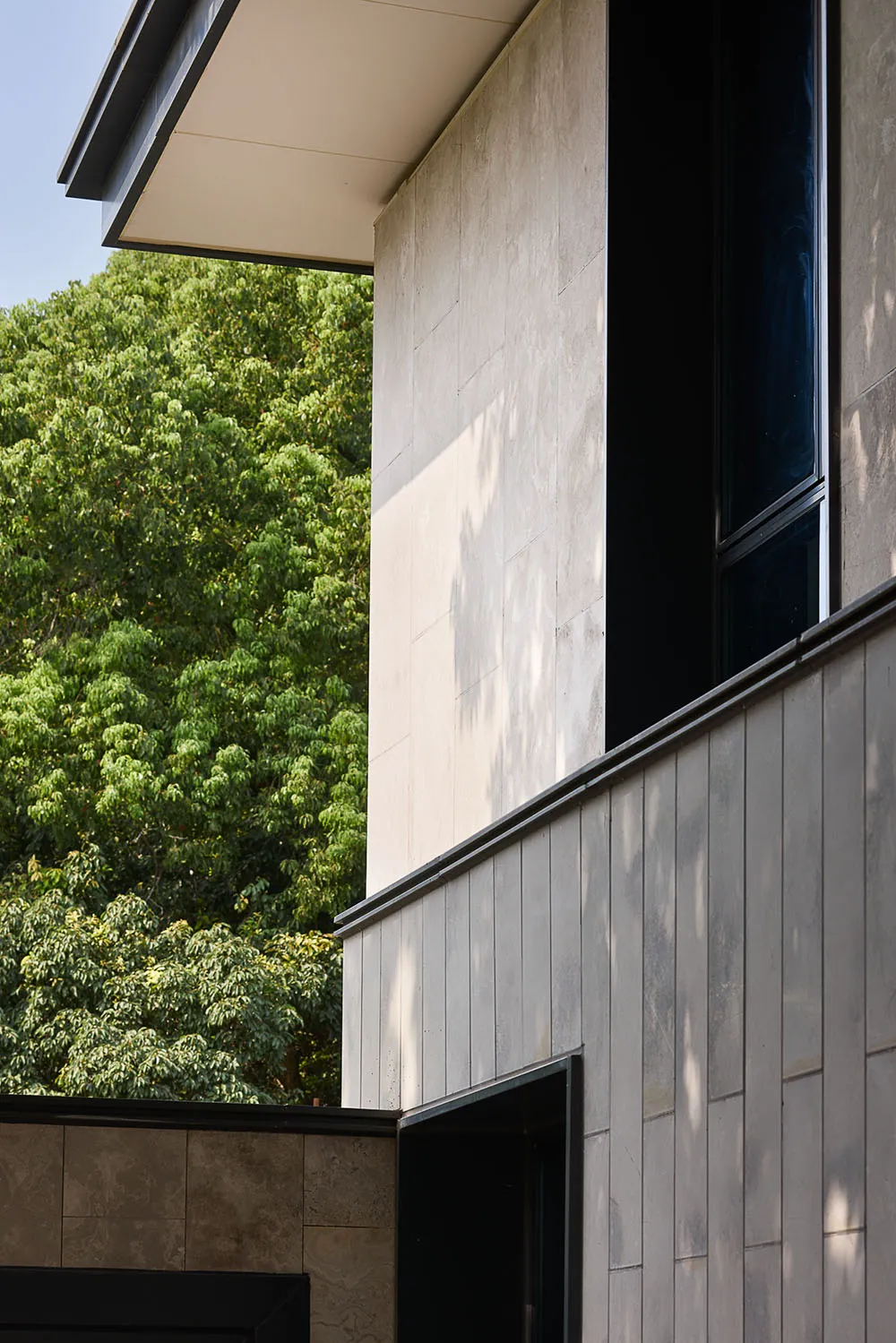 A modern building with a large glass window, surrounded by trees, and filled with natural light