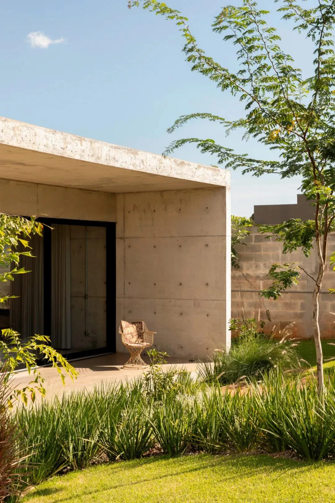 A concrete patio area with two wooden chairs, one near the left side and one near the center, in a relaxing outdoor space
