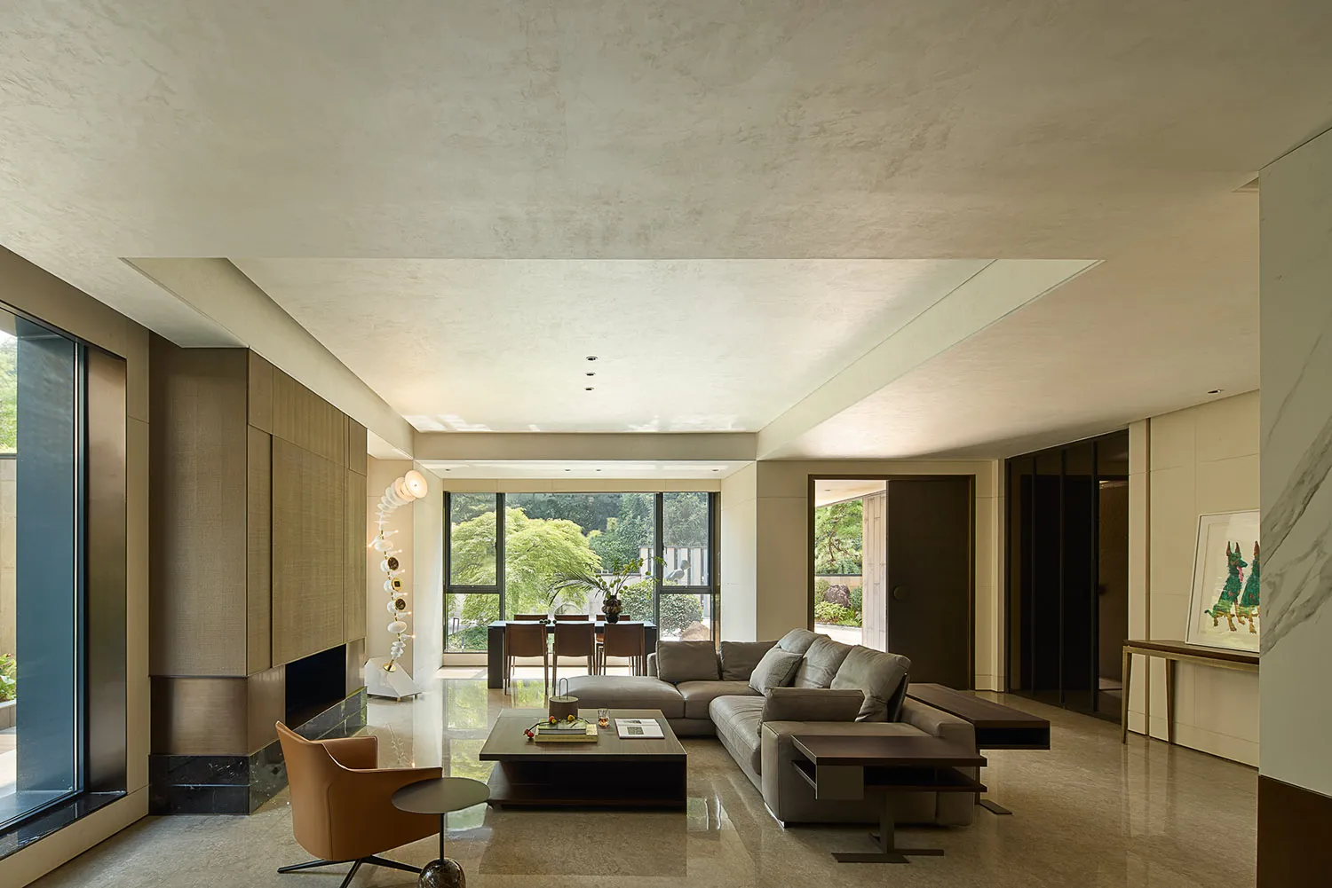 Open living area with a large couch, two chairs, and potted plants, surrounded by white walls and wooden furniture