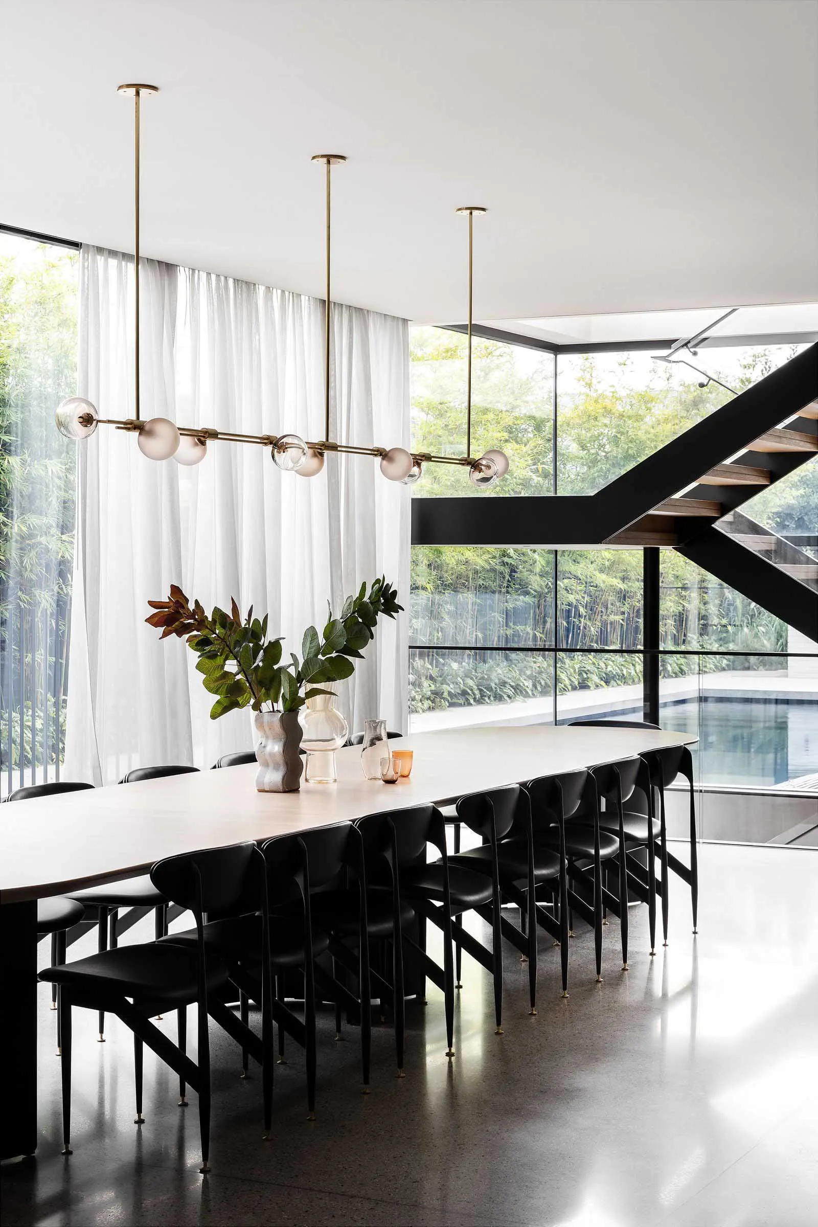 Elegant dining space with a white table, black chairs, and a vase of flowers, surrounded by comfortable seating for guests
