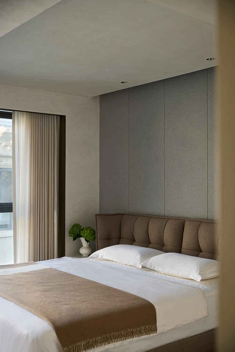Cozy bedroom with a plush bed, a vase, and natural light from a window
