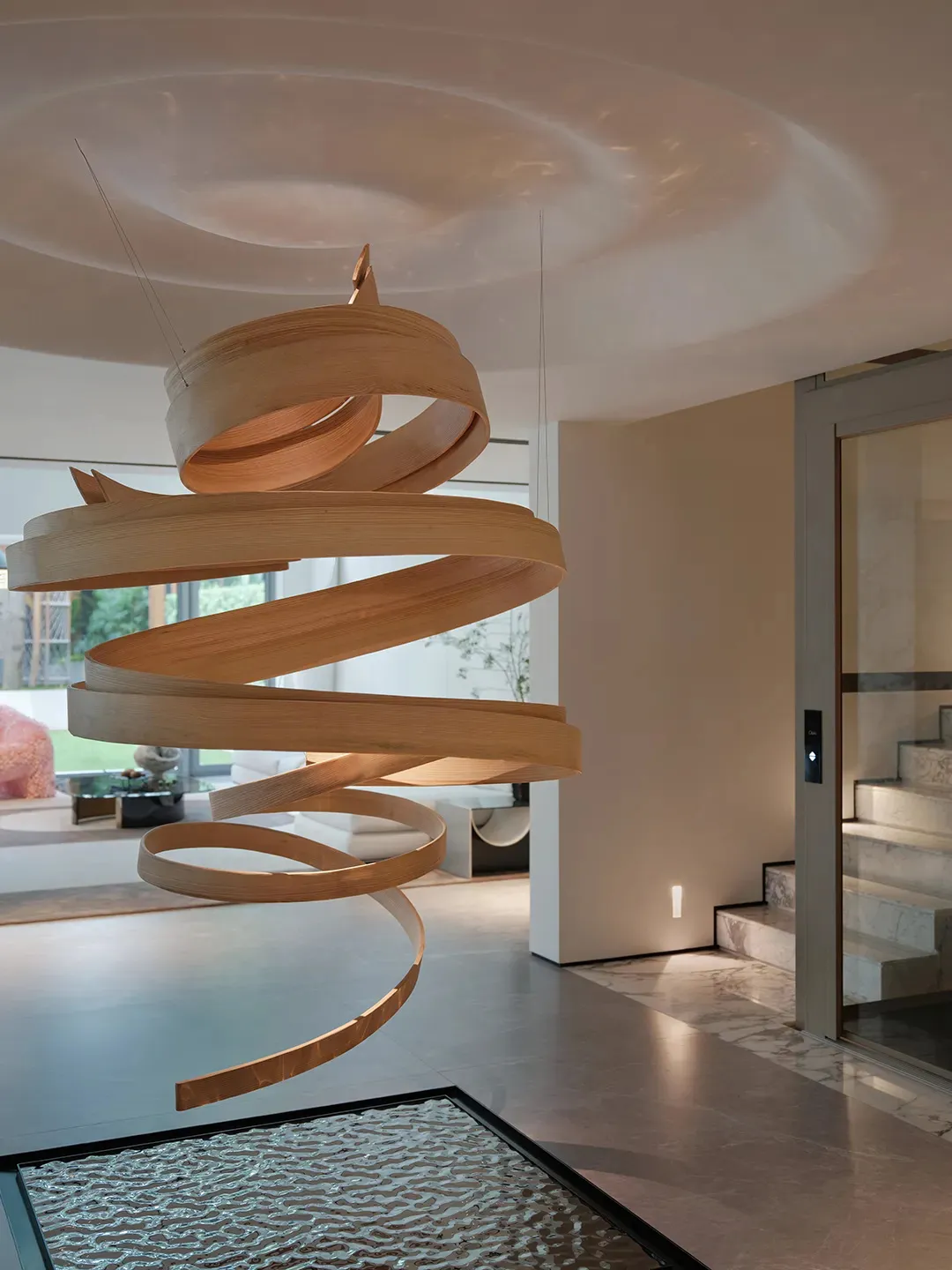 Open living area with a spiral wood sculpture, staircase, and warm lighting