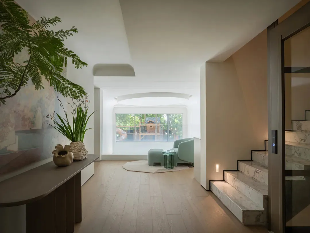 Cozy living area with hardwood floors, white walls, two chairs, a potted plant, and a vase