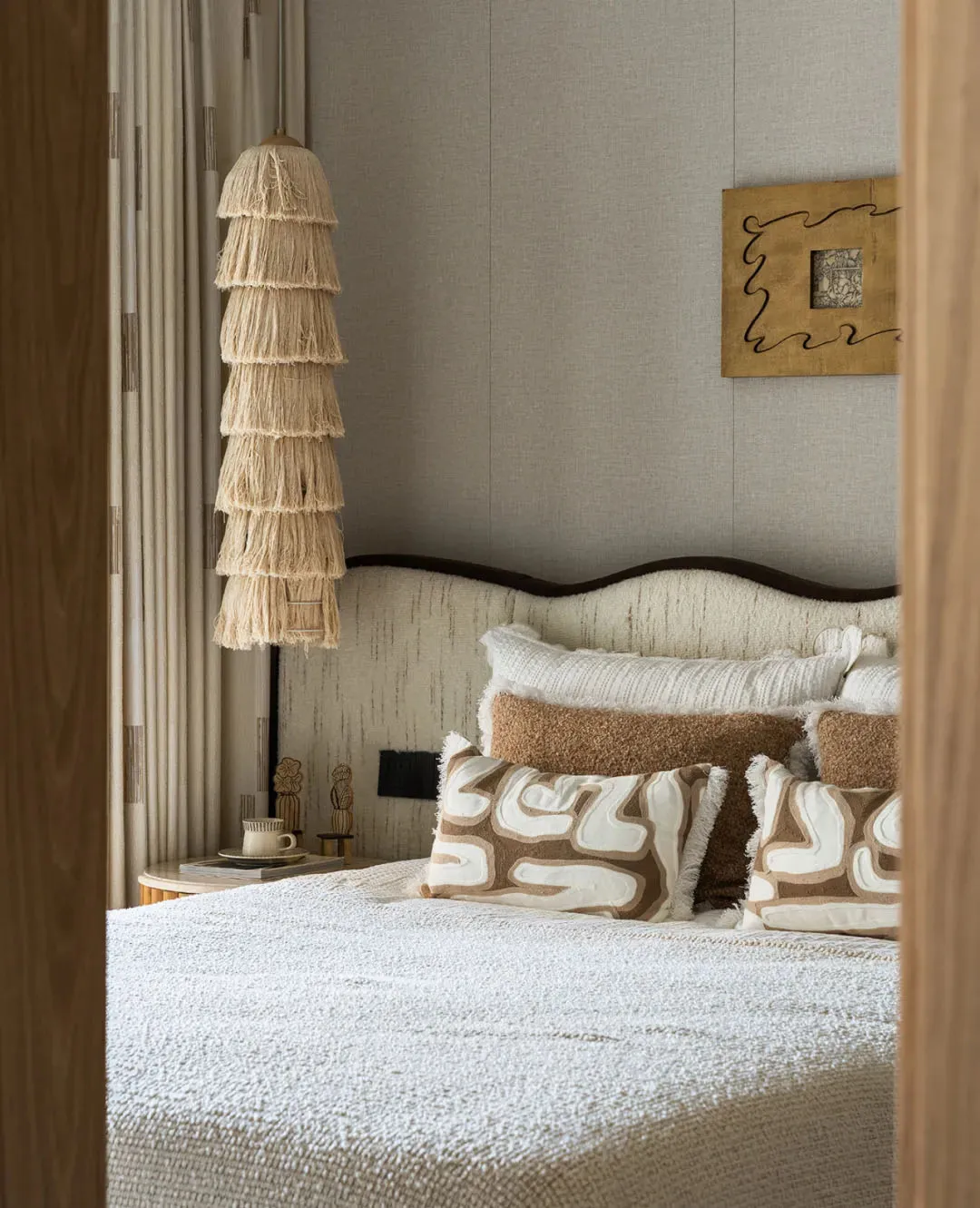 Cozy bedroom with a white bed, brown pillows, a wicker lamp, and a standard lamp, a chair, and a dining table