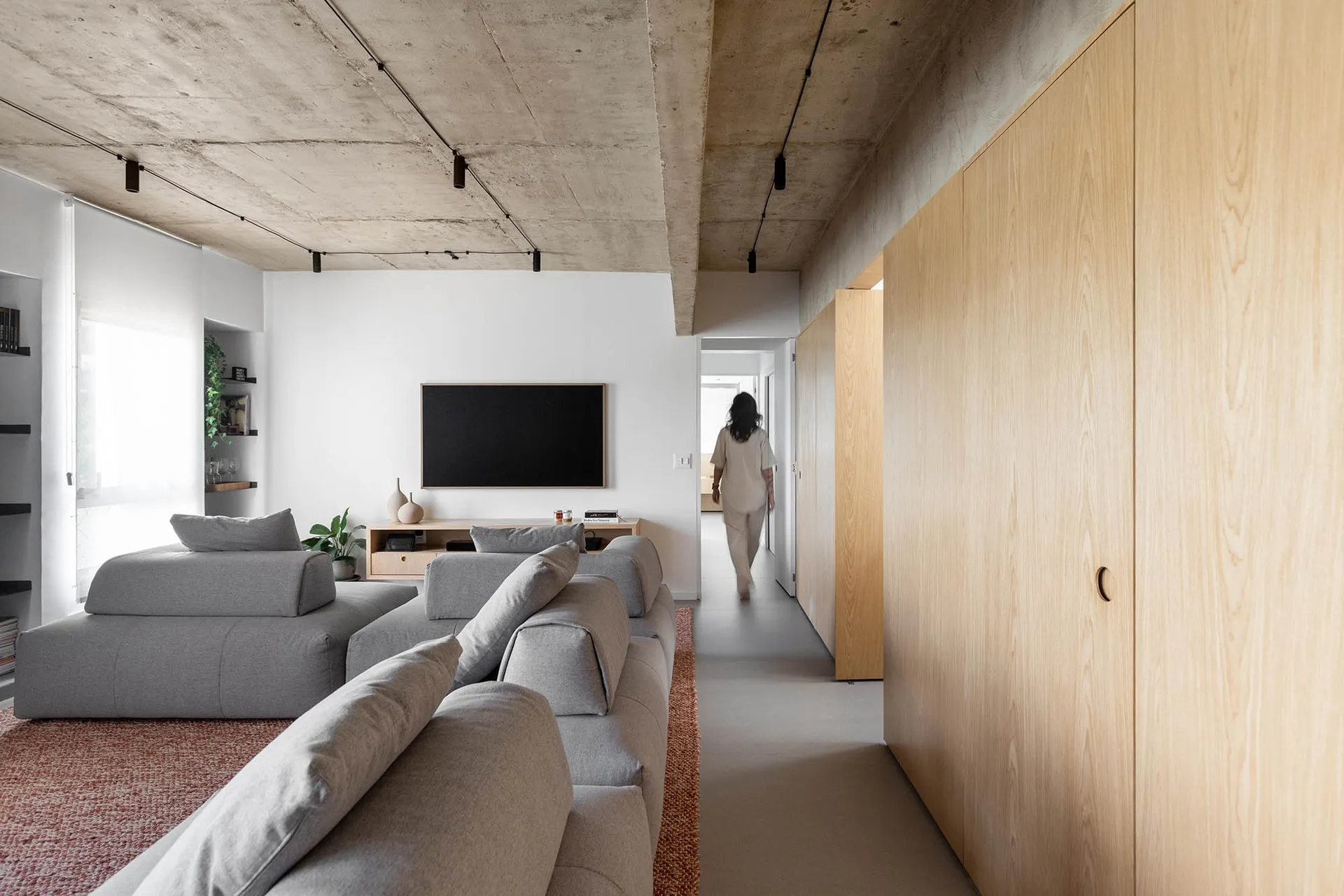 A comfortable open living area with a couch, chairs, TV, and potted plants, perfect for relaxation and socializing