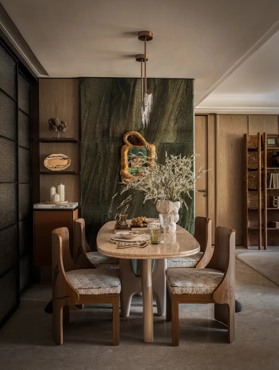 Dining area with a wooden table and chairs, surrounded by books and decorative items, creating a cozy atmosphere