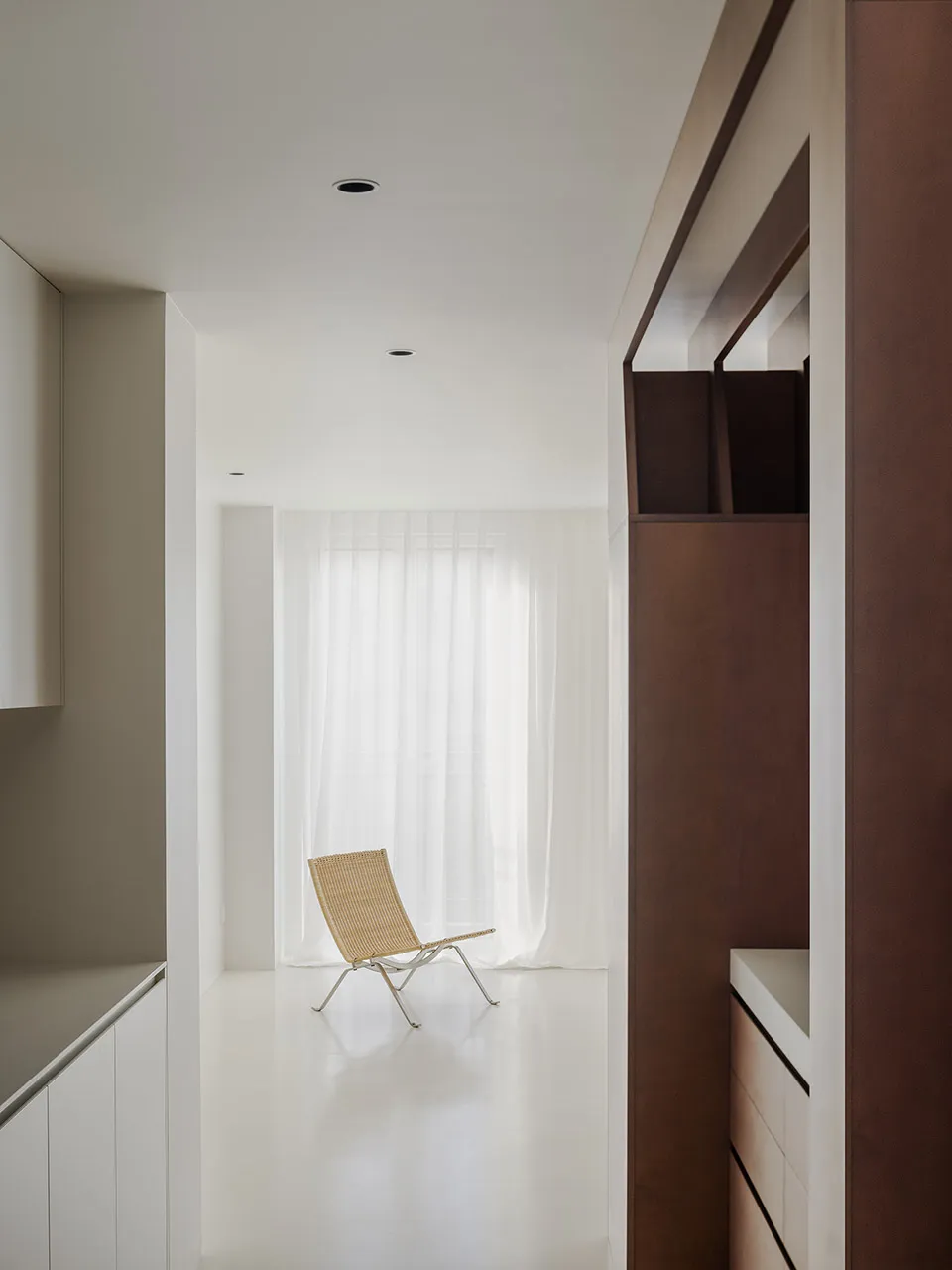 Empty white living room with a wooden floor, two chairs, and natural light from windows