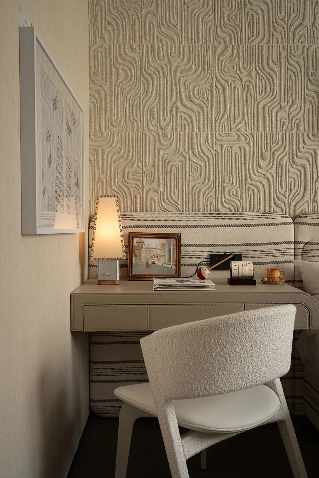 A cozy study area with a white chair, a desk, a lamp, books, and cups, creating a warm and inviting atmosphere