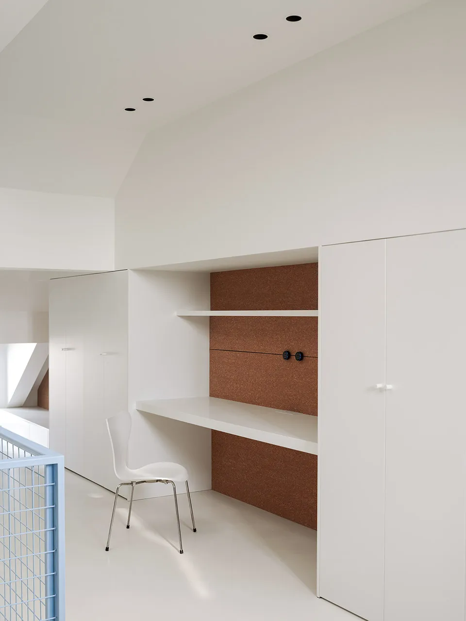 A minimalist living space with a white chair and desk, surrounded by a clean and airy atmosphere with visible stairs