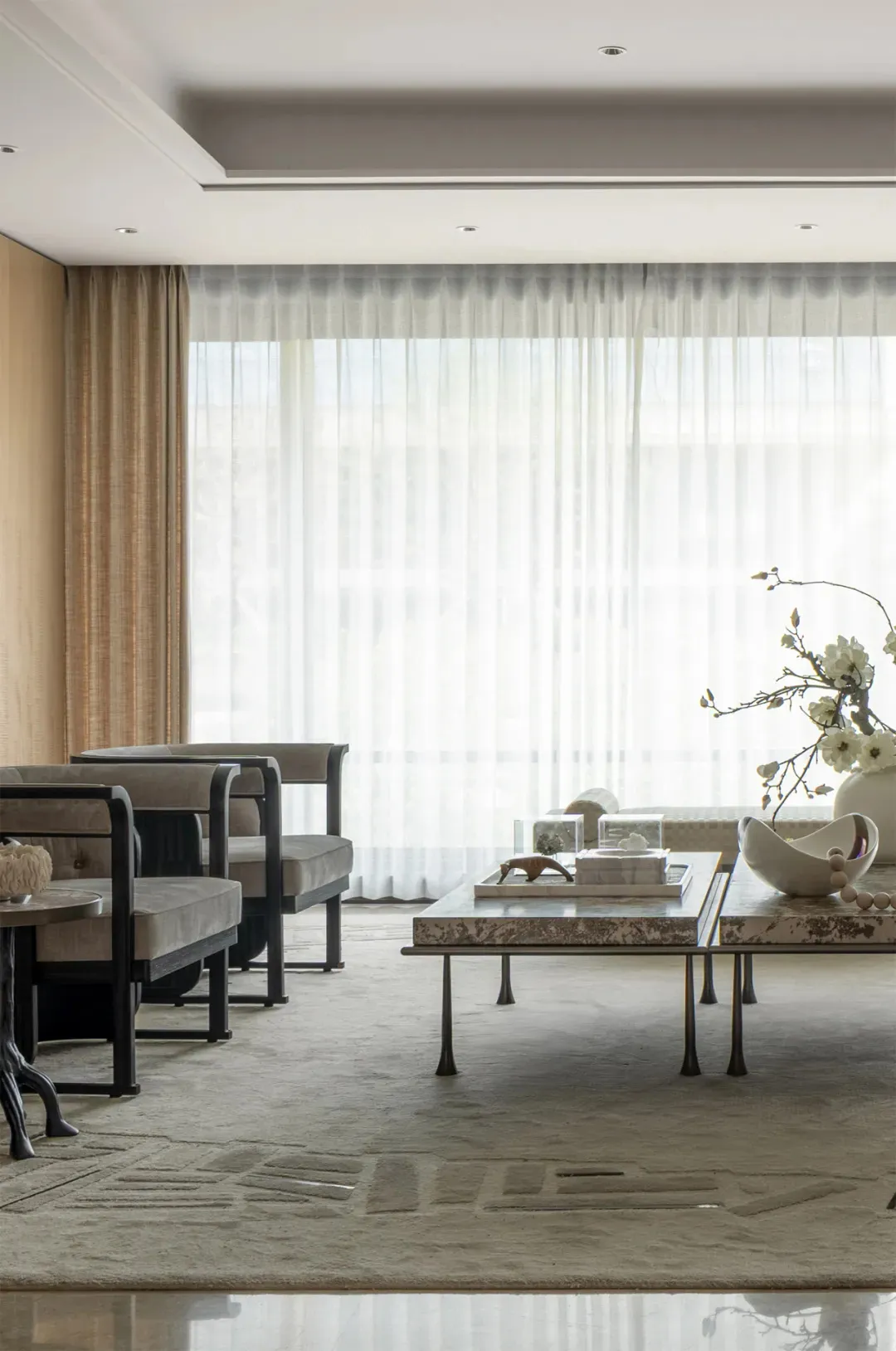 Warm and inviting living room with three couches, two chairs, and two dining tables, surrounded by white curtains