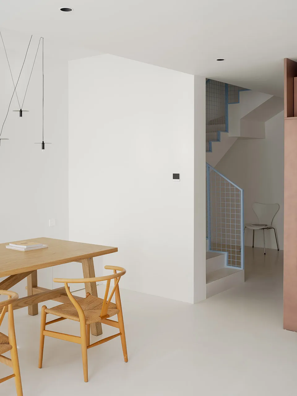Open dining space with a white color scheme, concrete walls, and a dining table surrounded by chairs