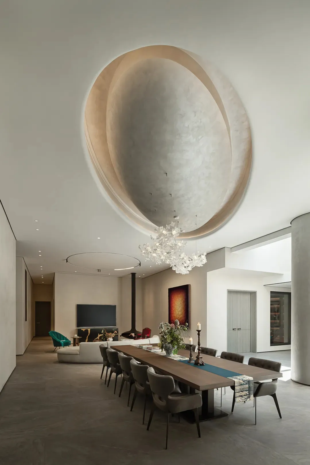 Open concept living area with a large window, multiple dining tables, couches, and decorative elements, exuding a warm and inviting atmosphere