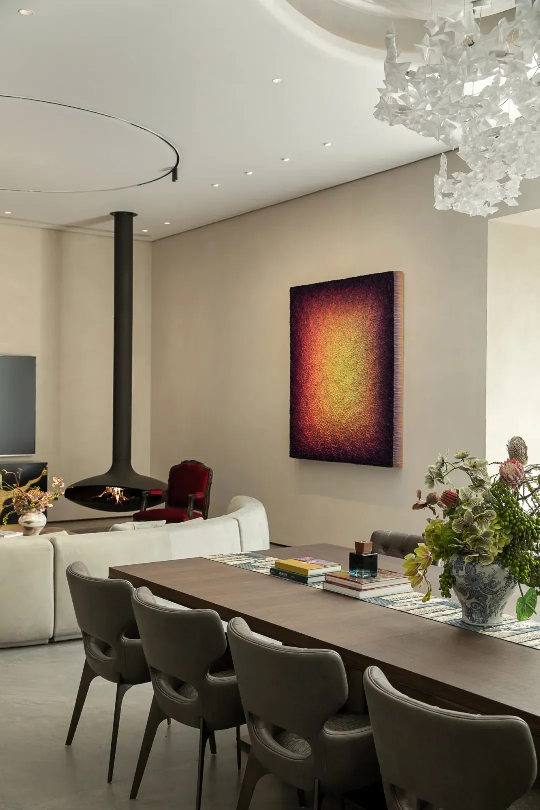 Cozy living space with a dining table, chairs, paintings, and a fireplace, with books and vases adding to the aesthetic