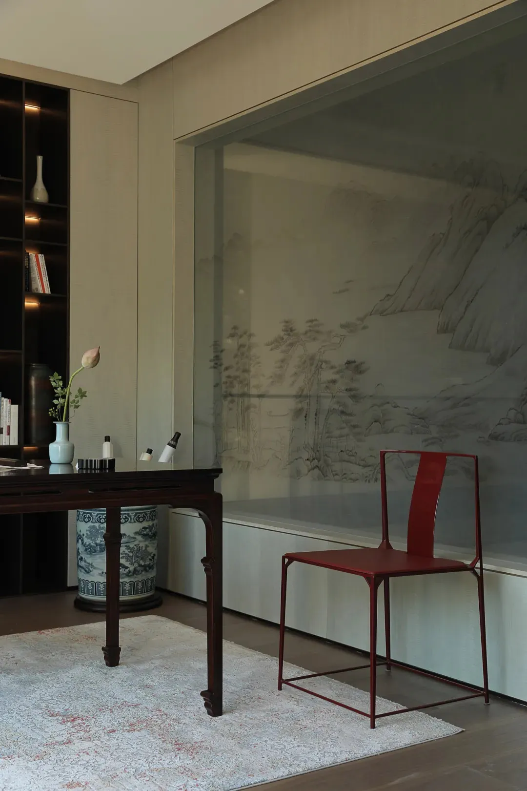 Cozy living space with a red chair, books, vases, and a table, inviting relaxation and leisure activities