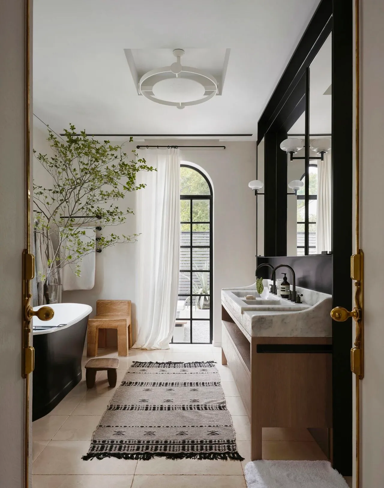 Luxurious bathroom with a white bathtub, two sinks, and a large window for natural light