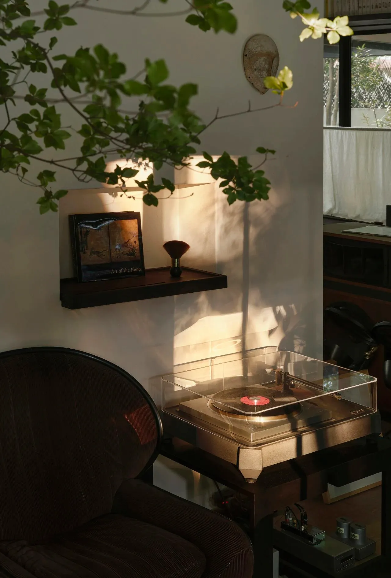 Cozy modern living space with a chair, table, and record player, surrounded by books in a home setting