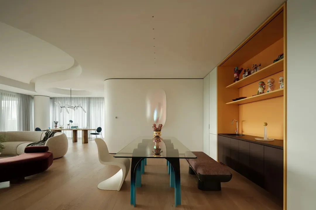 Open modern living space with a dining table, chairs, a couch, and a vase, well-lit and inviting