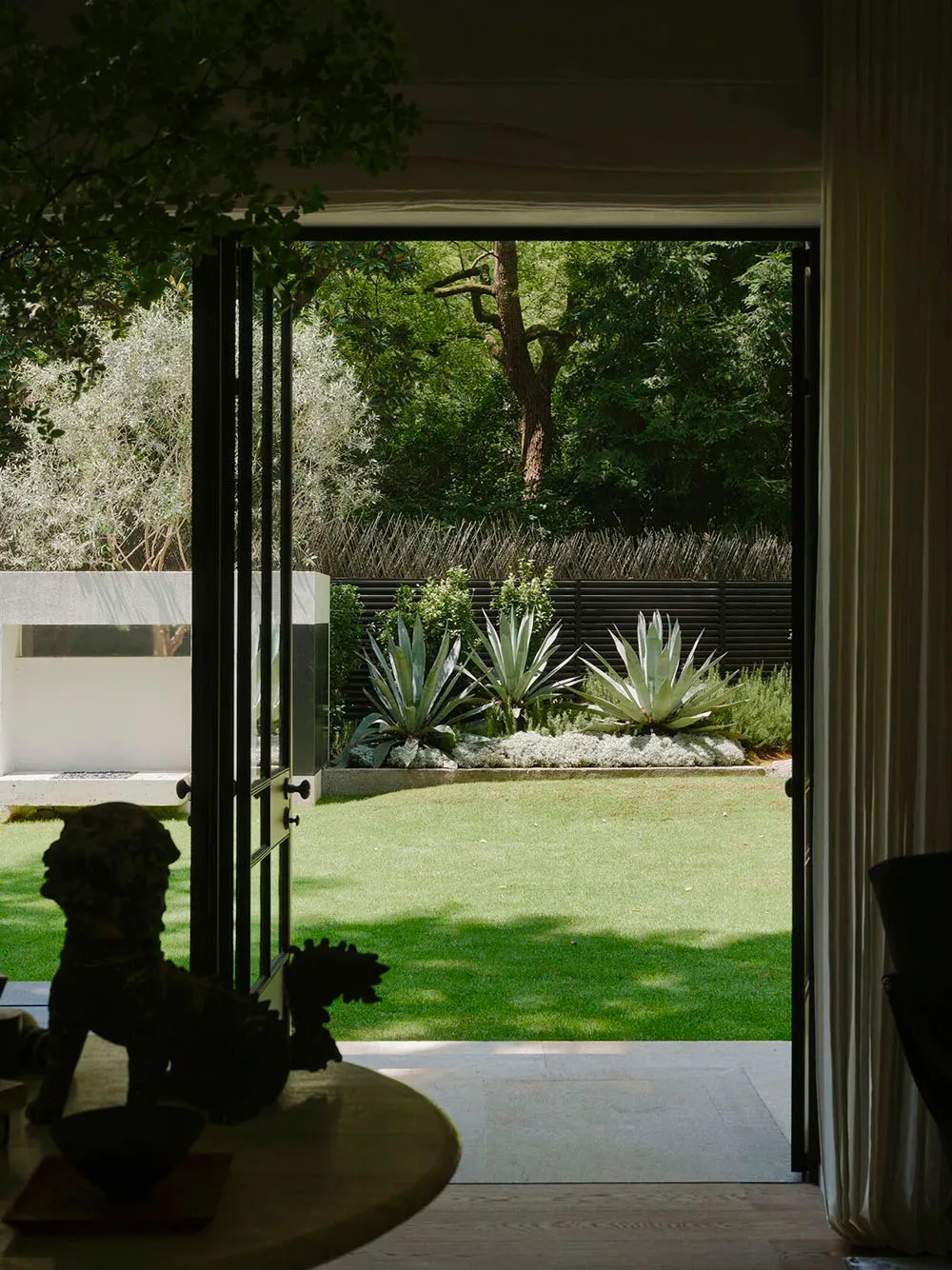 A well-maintained outdoor living area with a green lawn, potted plants, and a patio