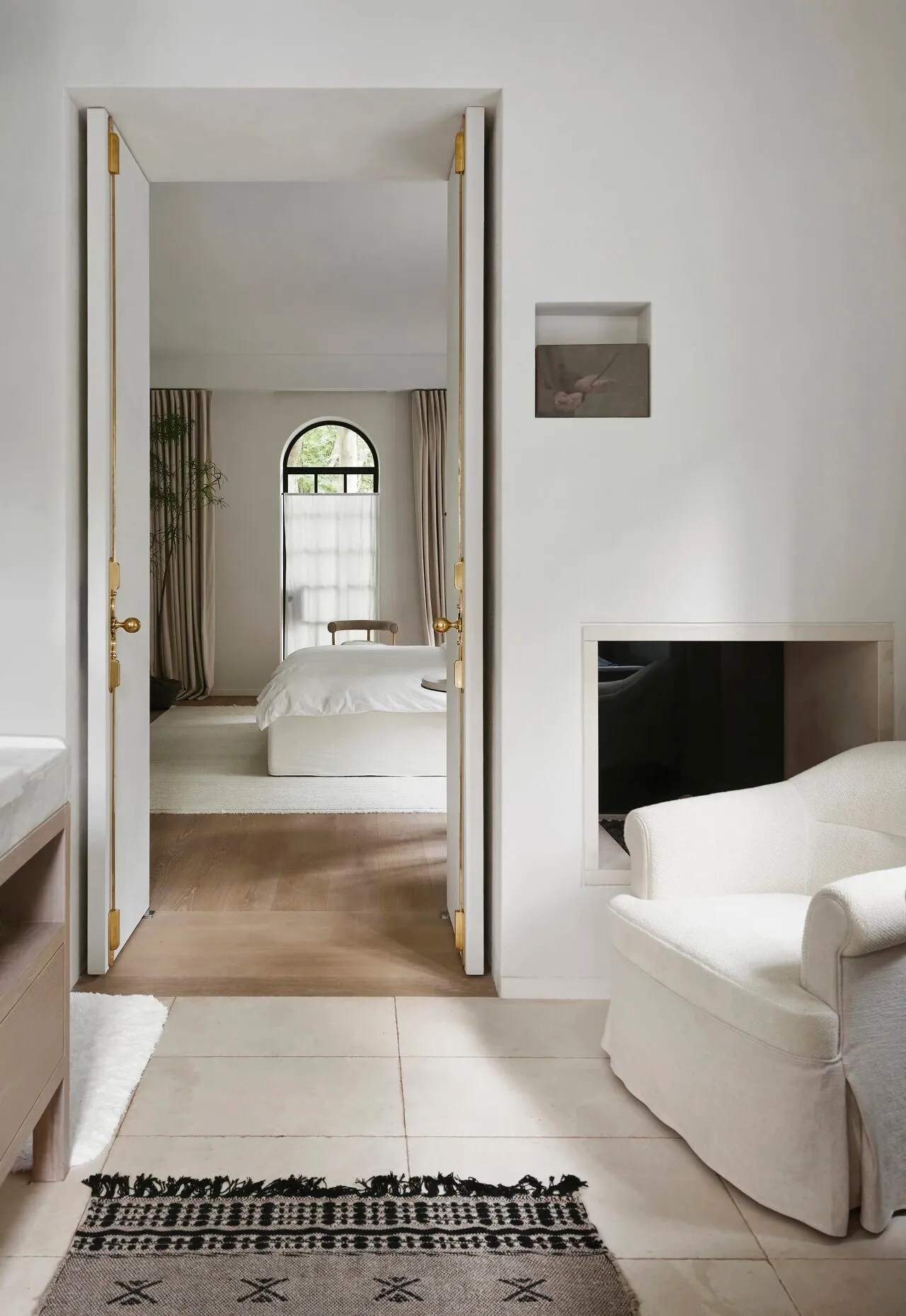 Open living area with a bed in the bedroom and a sofa in the living room, surrounded by natural light and greenery