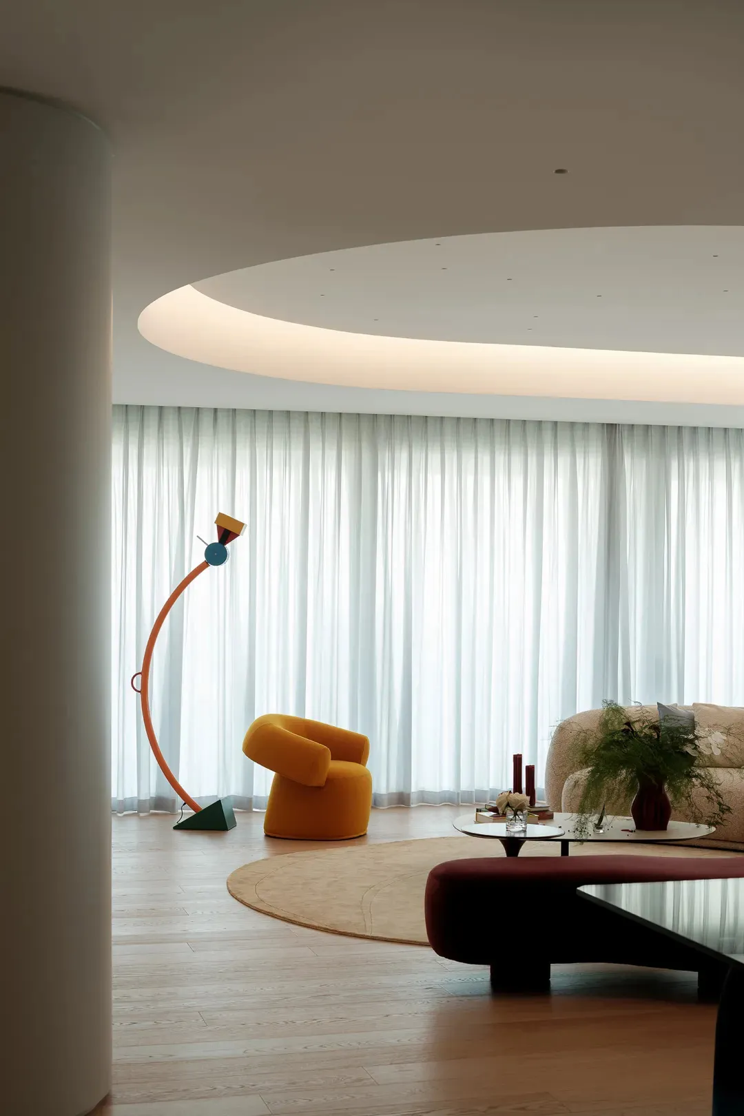 Open living space with a large couch, yellow chair, dining table, potted plants, and a vase, set against a neutral background
