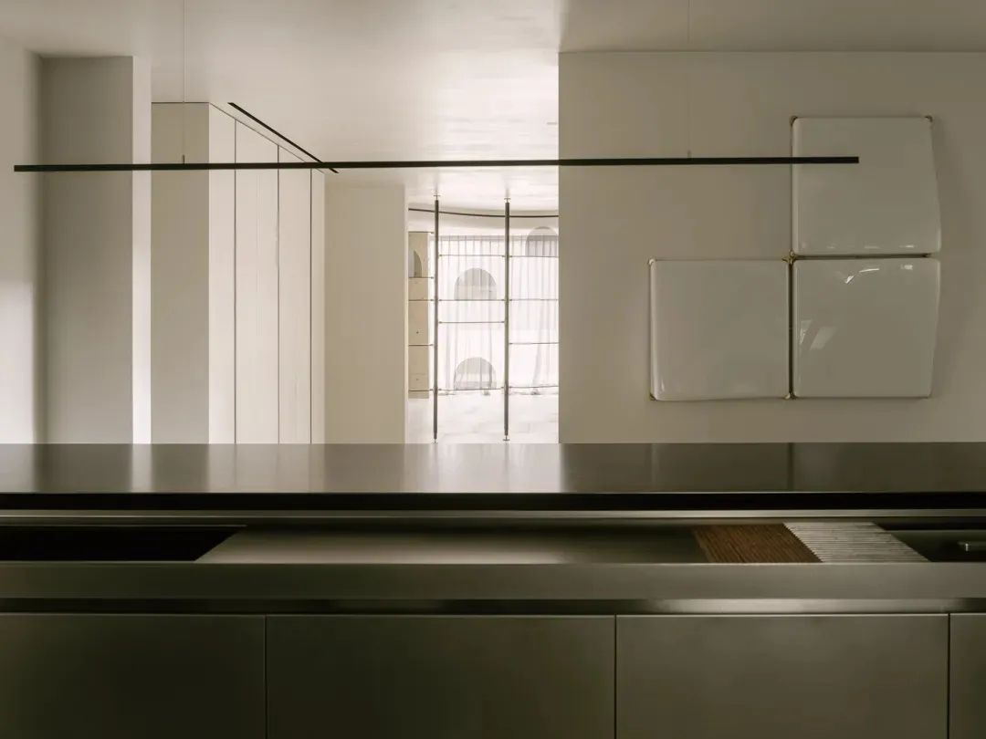 Empty kitchen with a stainless steel countertop island in a white-themed space with a bright and airy feel