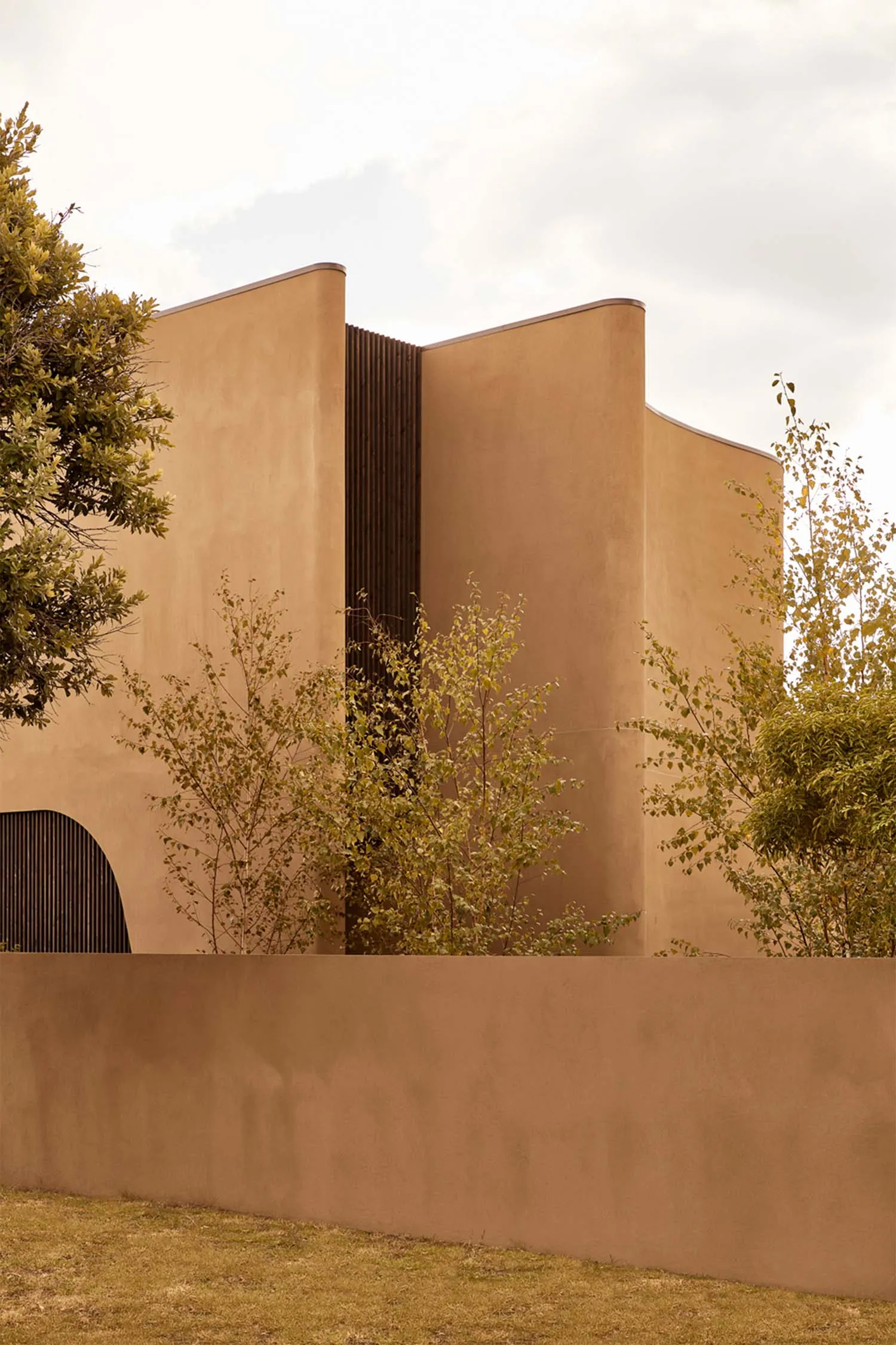 A modern house with a stucco exterior, surrounded by trees, creating a warm and inviting atmosphere
