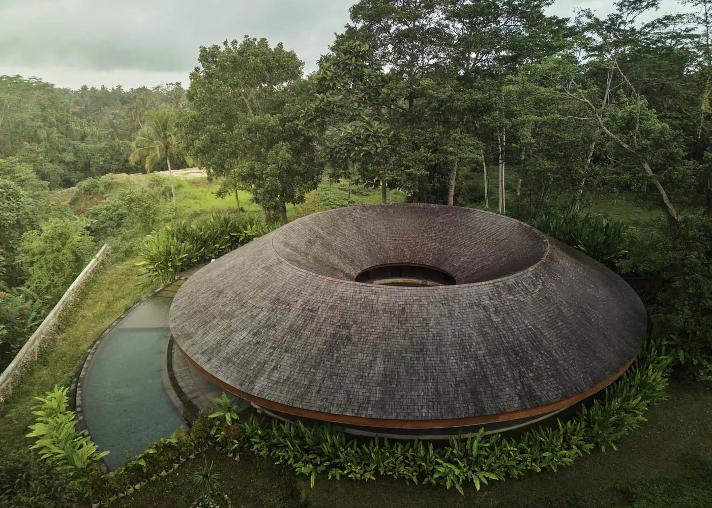 A modern house with a circular shape surrounded by trees, providing a sense of tranquility and connection to nature