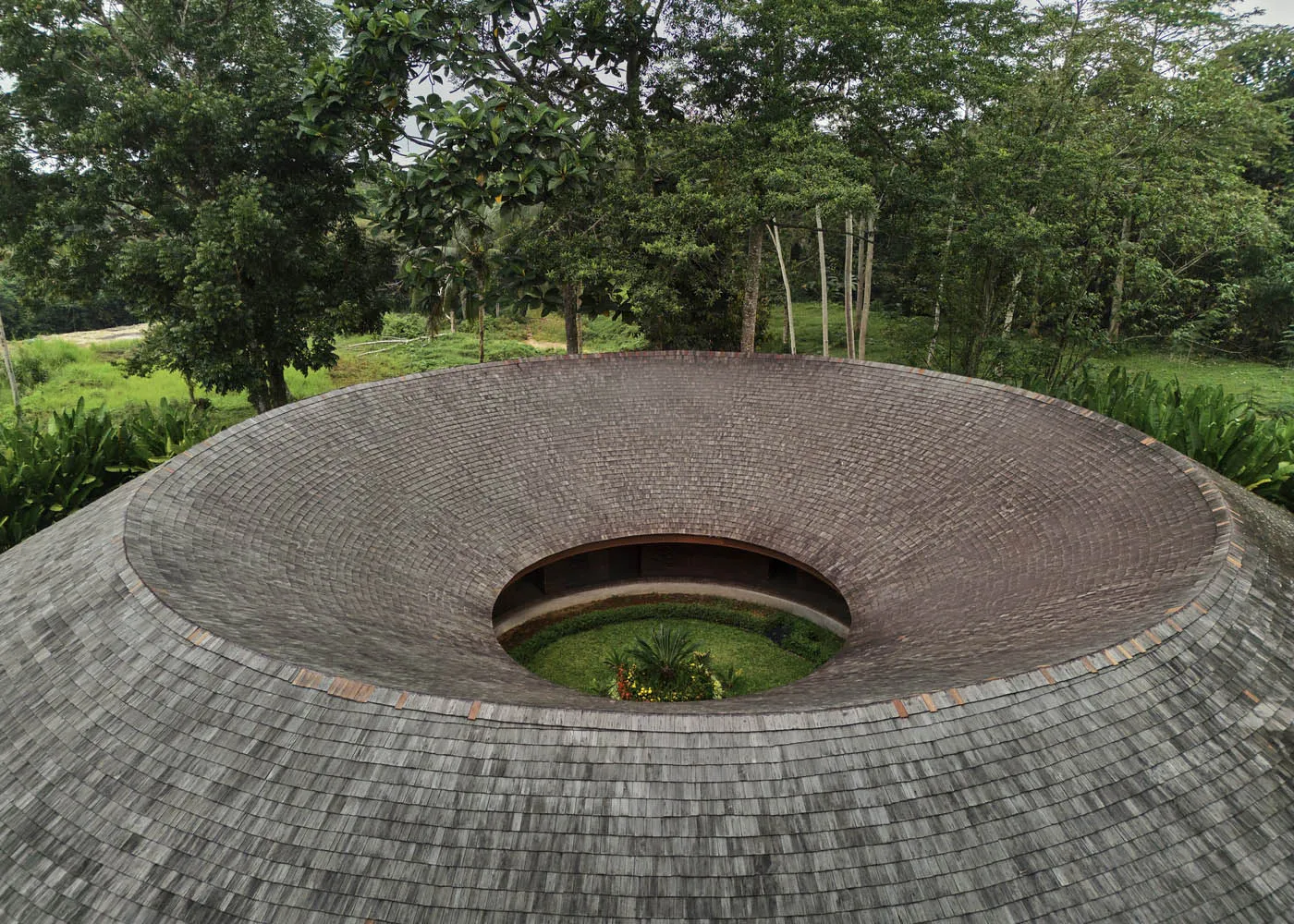 A serene interior space with a circular room featuring a stone-like appearance, potted plants, and a calm atmosphere