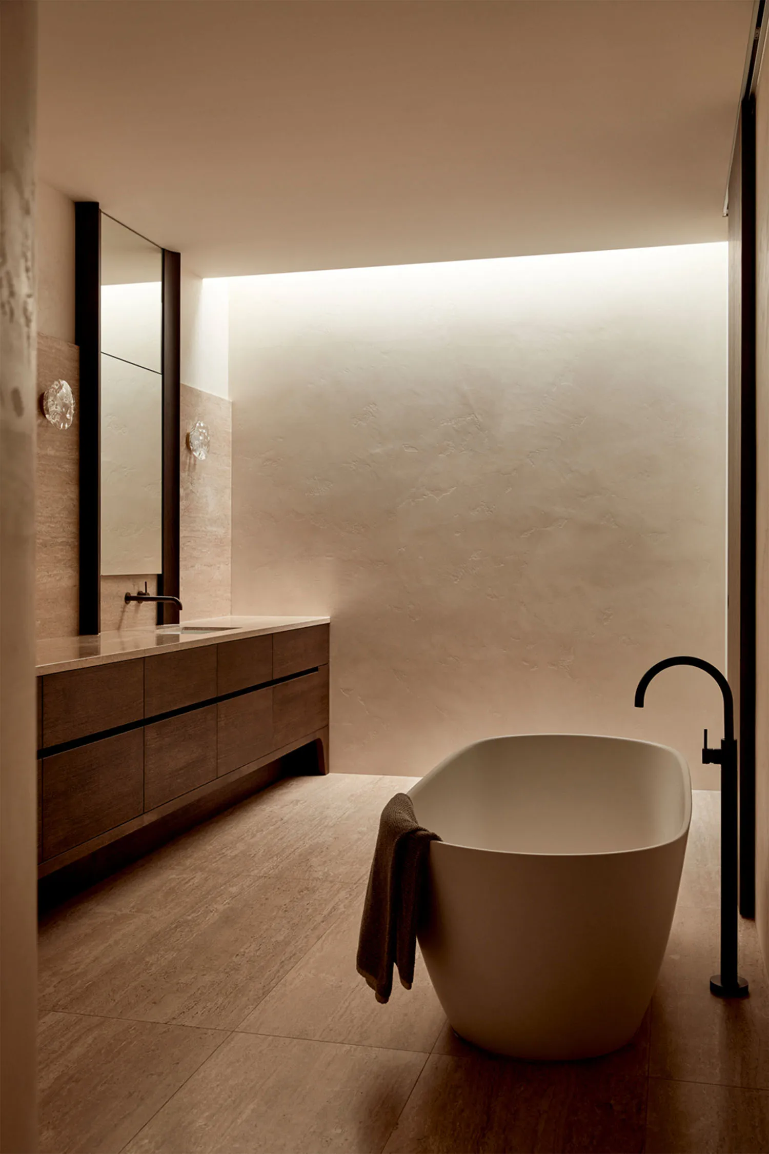 Bathroom with two sinks and a white bathtub, surrounded by stone walls for a calm and serene atmosphere