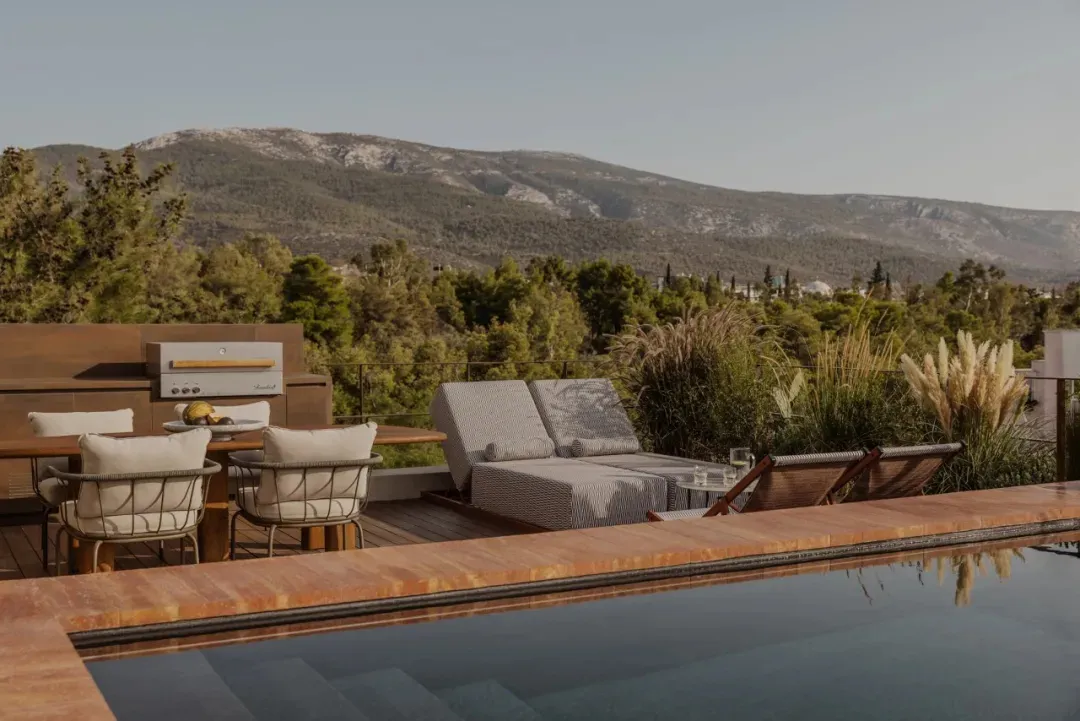 An outdoor living area with a wooden deck, a large glass pool table, and comfortable seating around it, with a nearby dining table