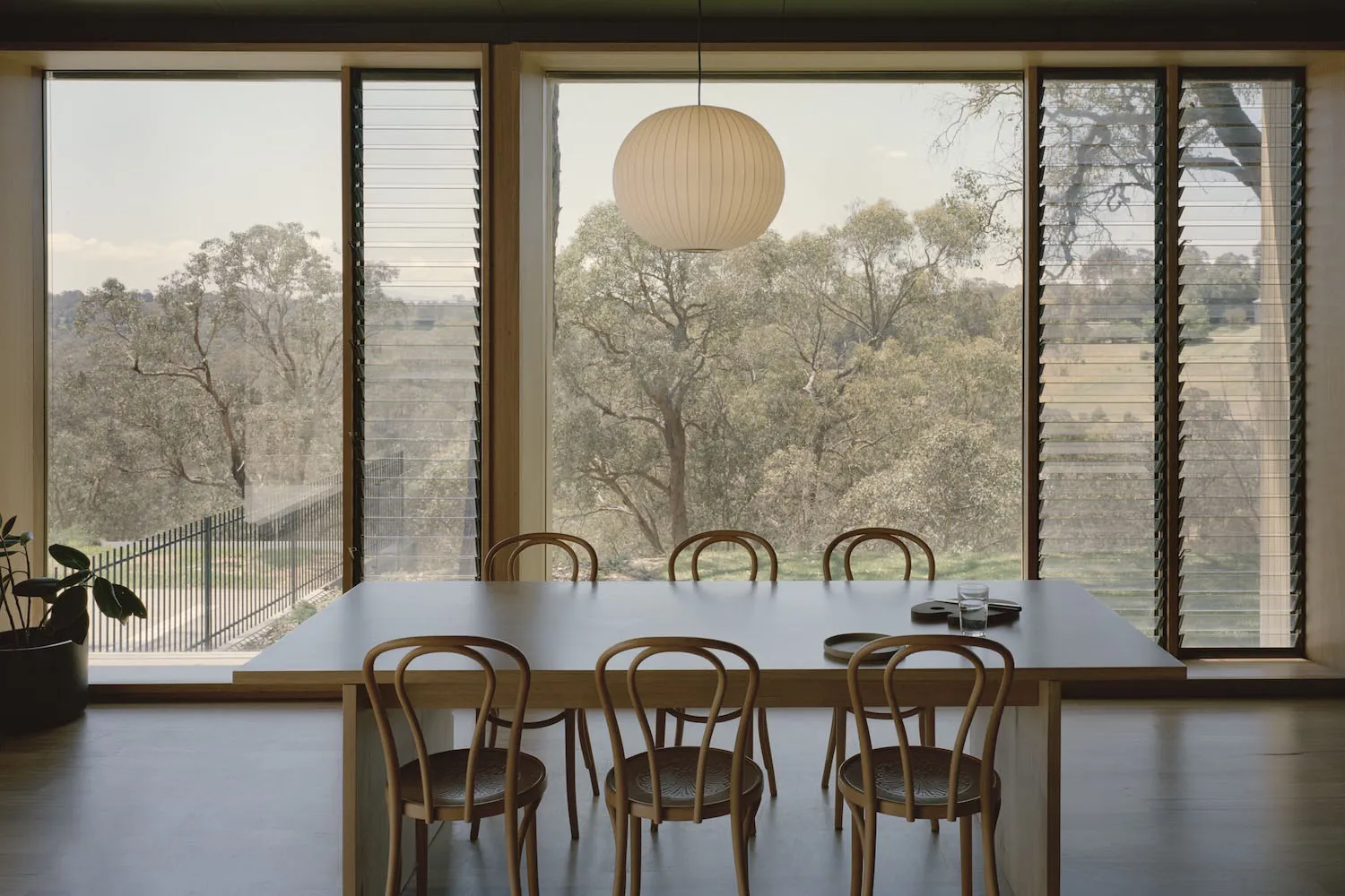 A warm and inviting dining area with a wooden table and chairs, surrounded by a symmetrical arrangement of additional chairs
