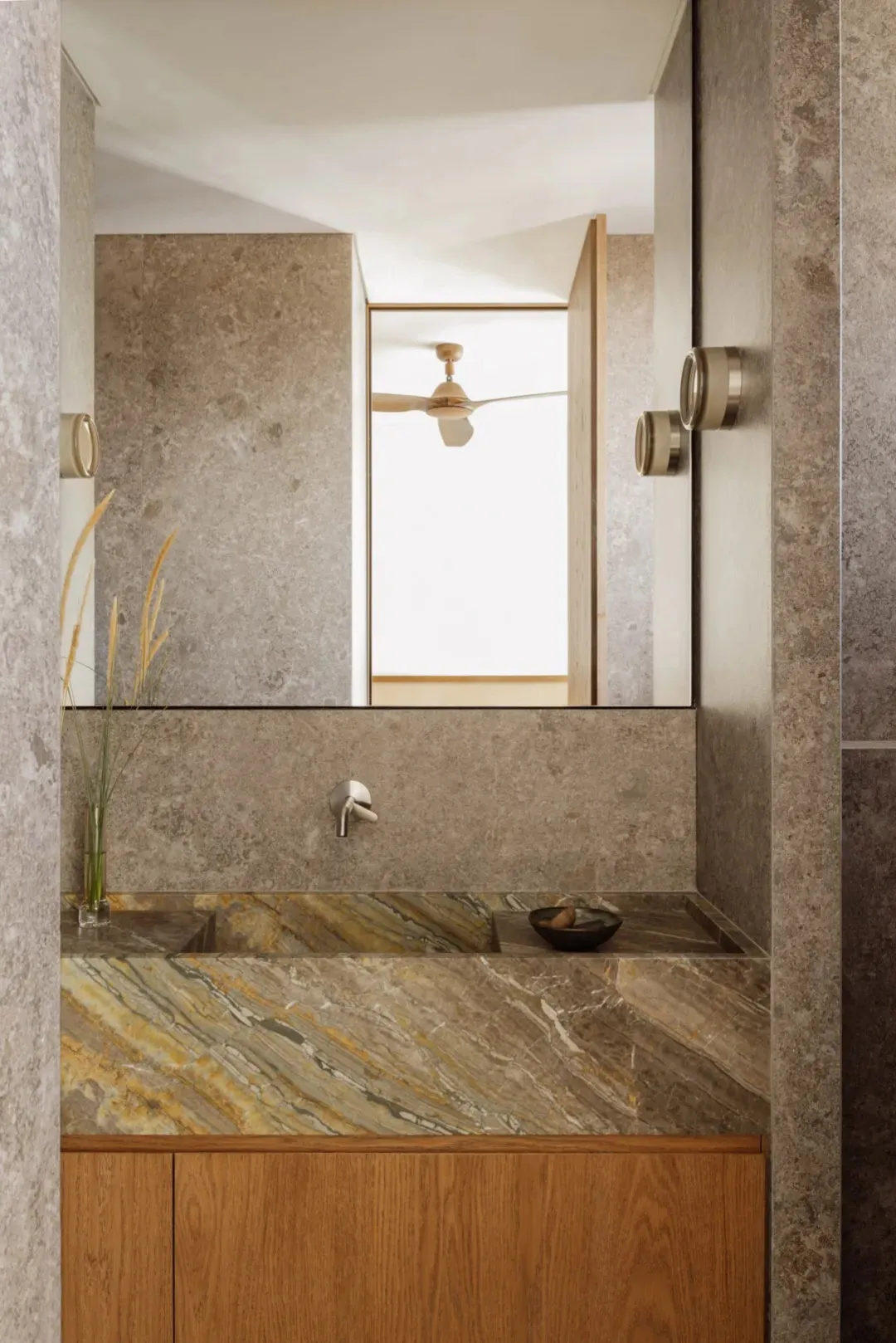 Modern bathroom with two sinks, marble countertops, and a ceiling fan above the mirror