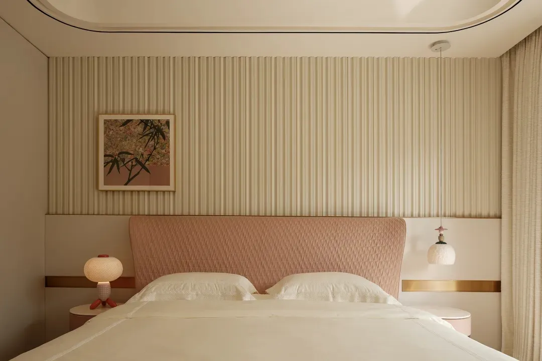 A cozy bedroom with a striped wall, a large bed, two lamps, and a painting above the bed