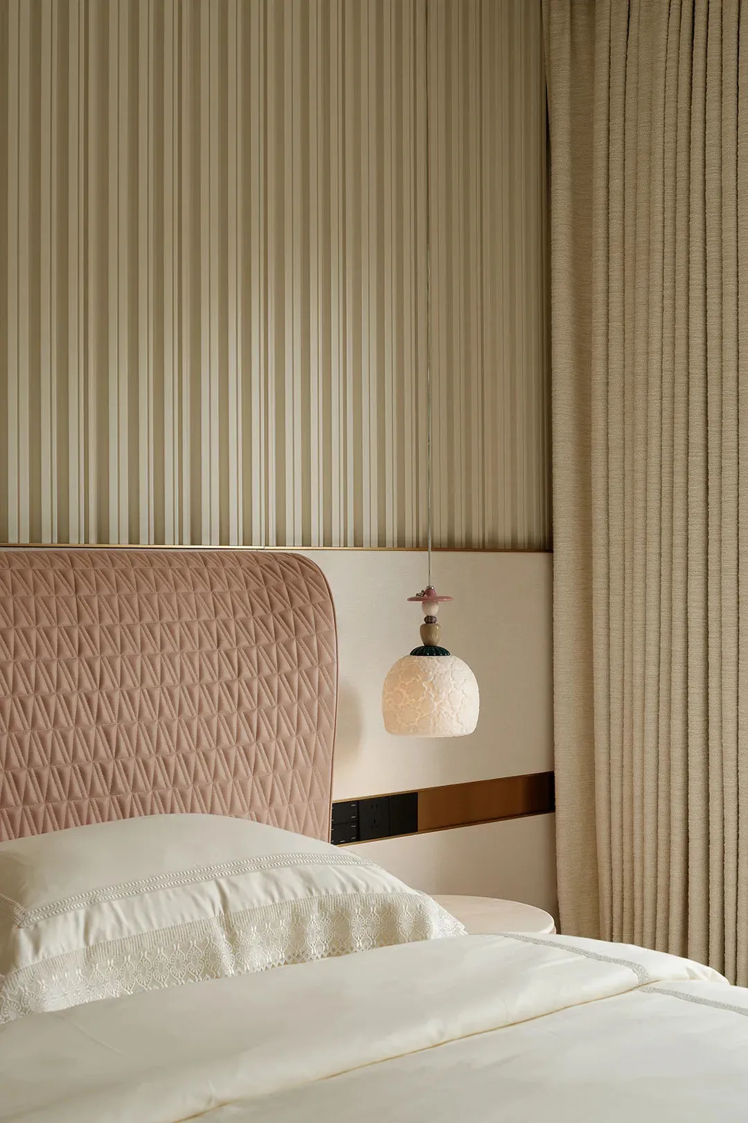 Cozy bedroom with a large bed featuring a pink headboard and striped design, two lamps, and a chair, creating a relaxing atmosphere