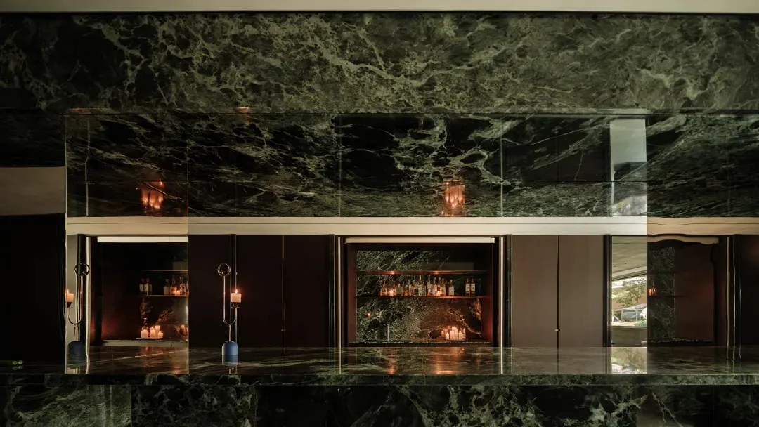 Elegant kitchen with a large marble countertop, bottles on the counter, and a sophisticated atmosphere