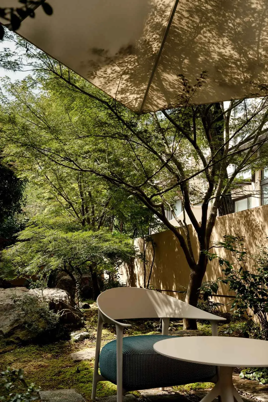 A cozy outdoor patio with a wooden bench, umbrella, and potted plants, creating a relaxing seating area