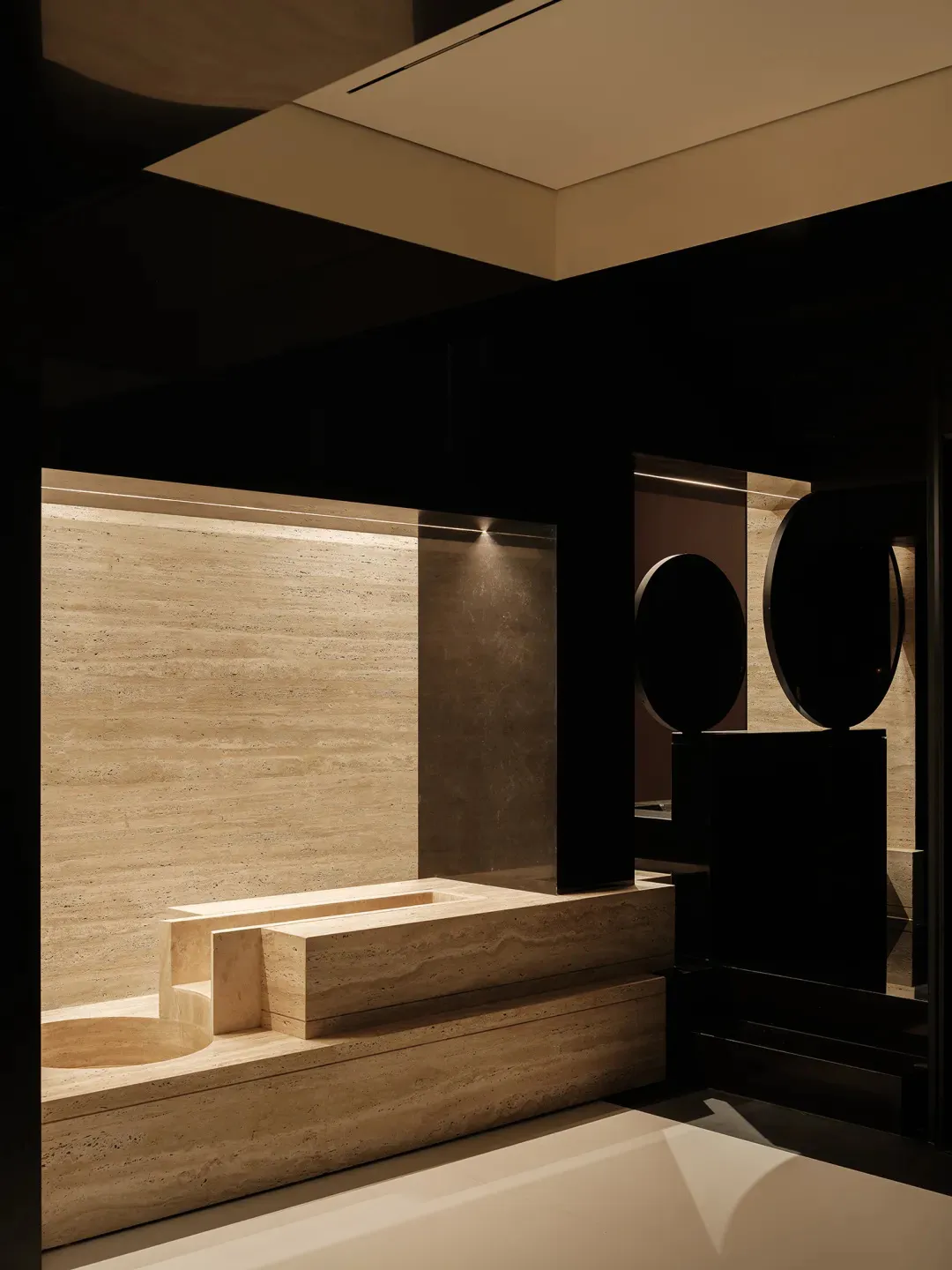 A dark and moody bathroom with a black and white color scheme, featuring a sink and toilet, and two round objects, one near the sink and another near the toilet