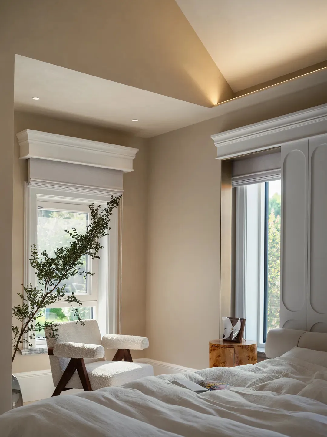 Cozy bedroom with a sitting area featuring two chairs, a potted plant, and a vase, creating a relaxing atmosphere