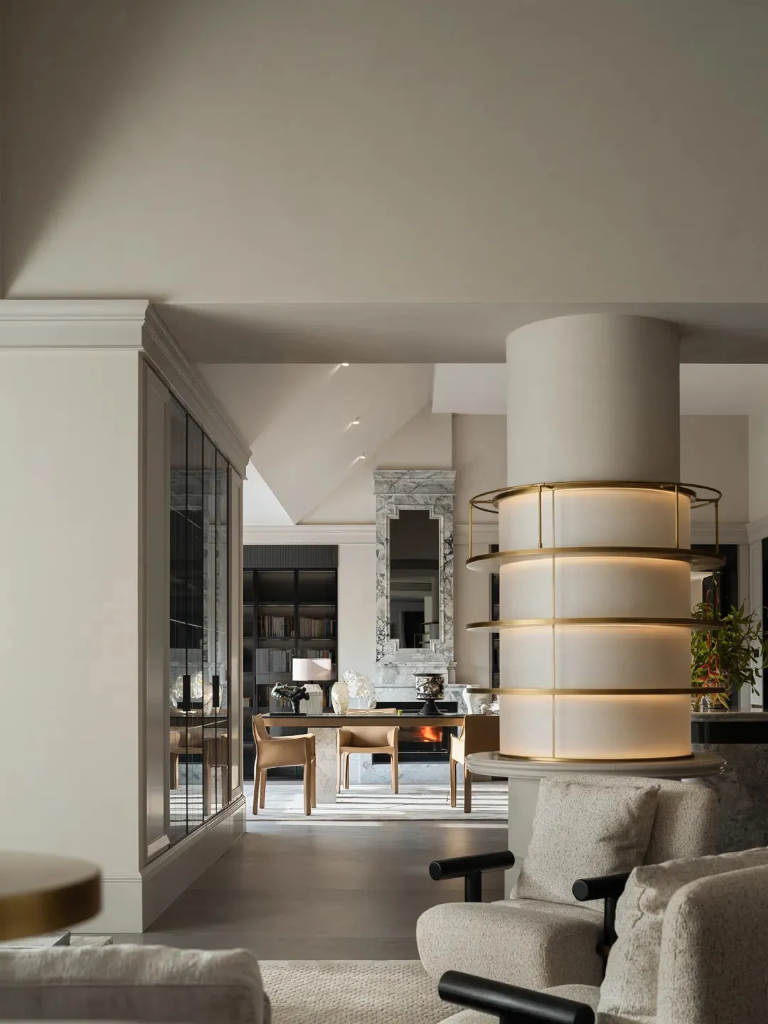 Open modern living space with a white circular column, clean lines, minimal decor, and multiple seating areas with potted plants