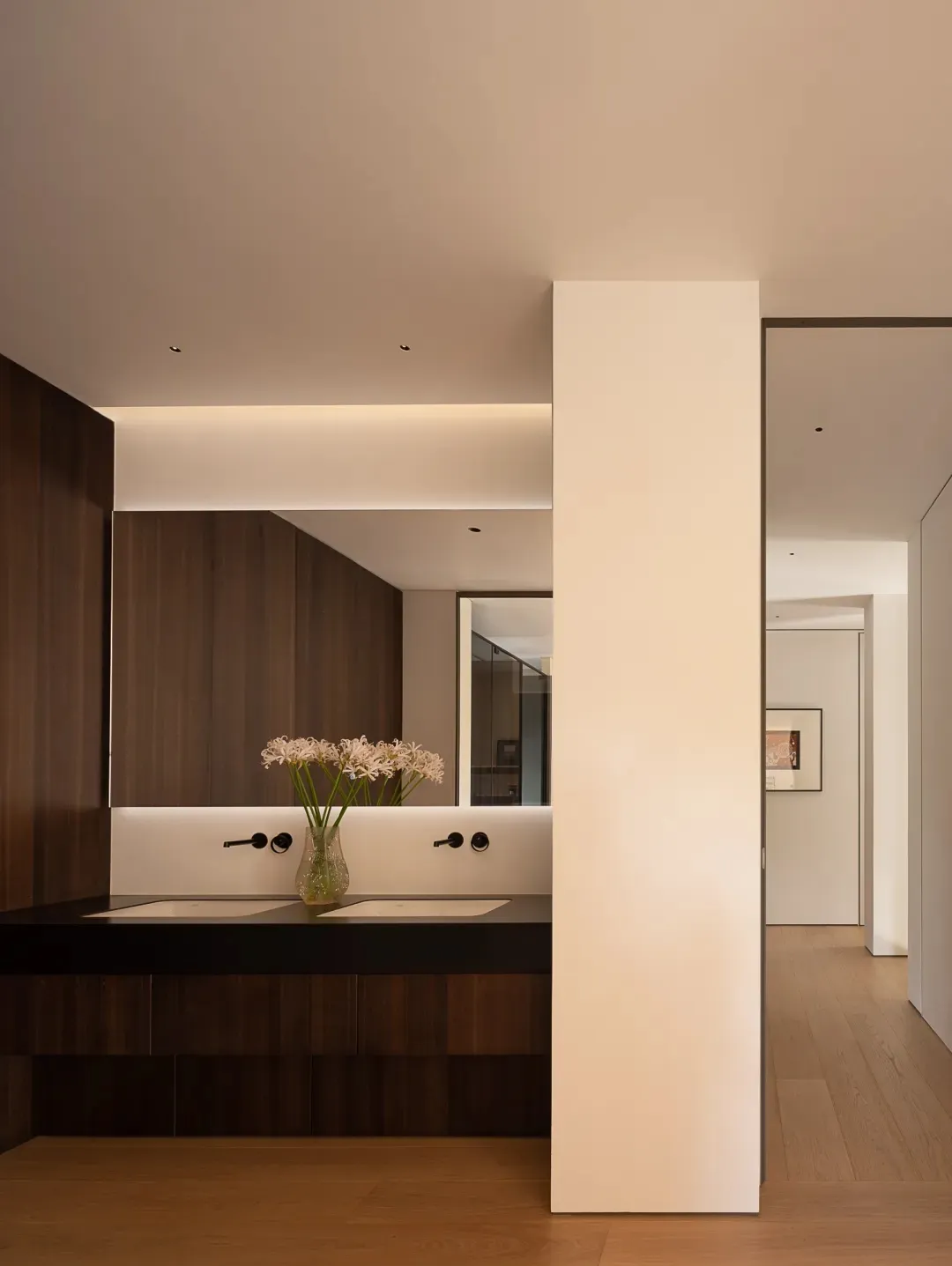 Modern bathroom with two sinks, wooden accents, and elegant vases, creating a warm and inviting atmosphere