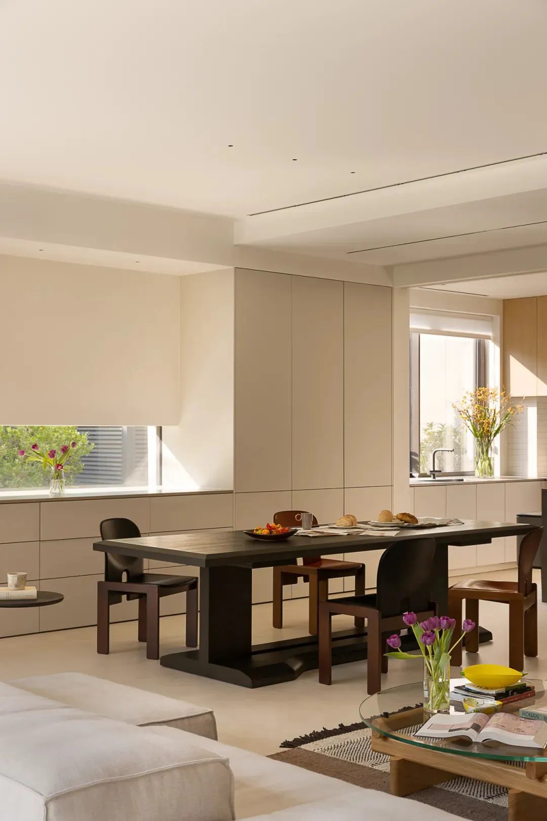 Bright and inviting open concept kitchen and dining area with a large table, chairs, vases, and natural light from windows
