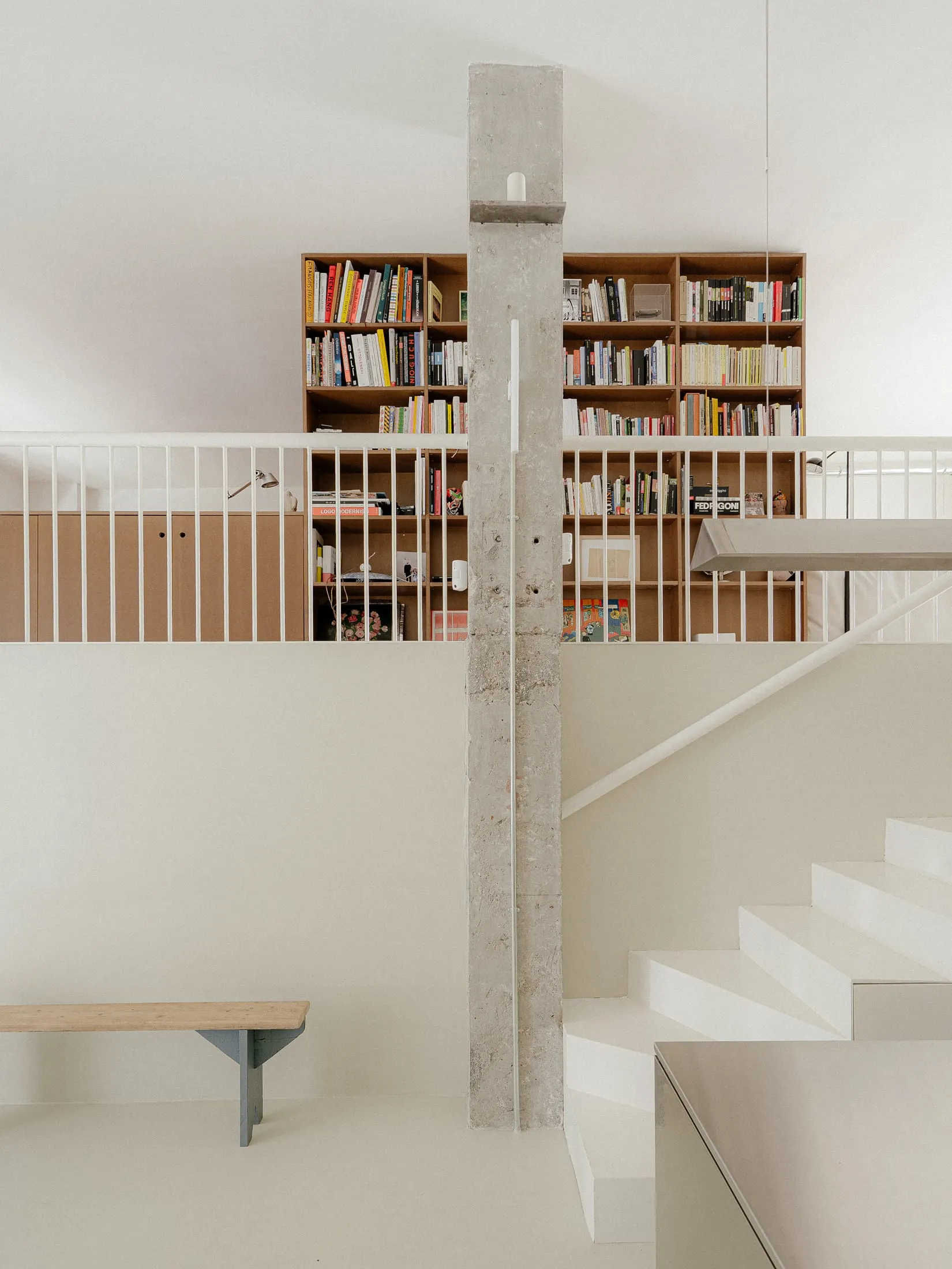 Residential interior with a wooden staircase, scattered books, and a warm atmosphere