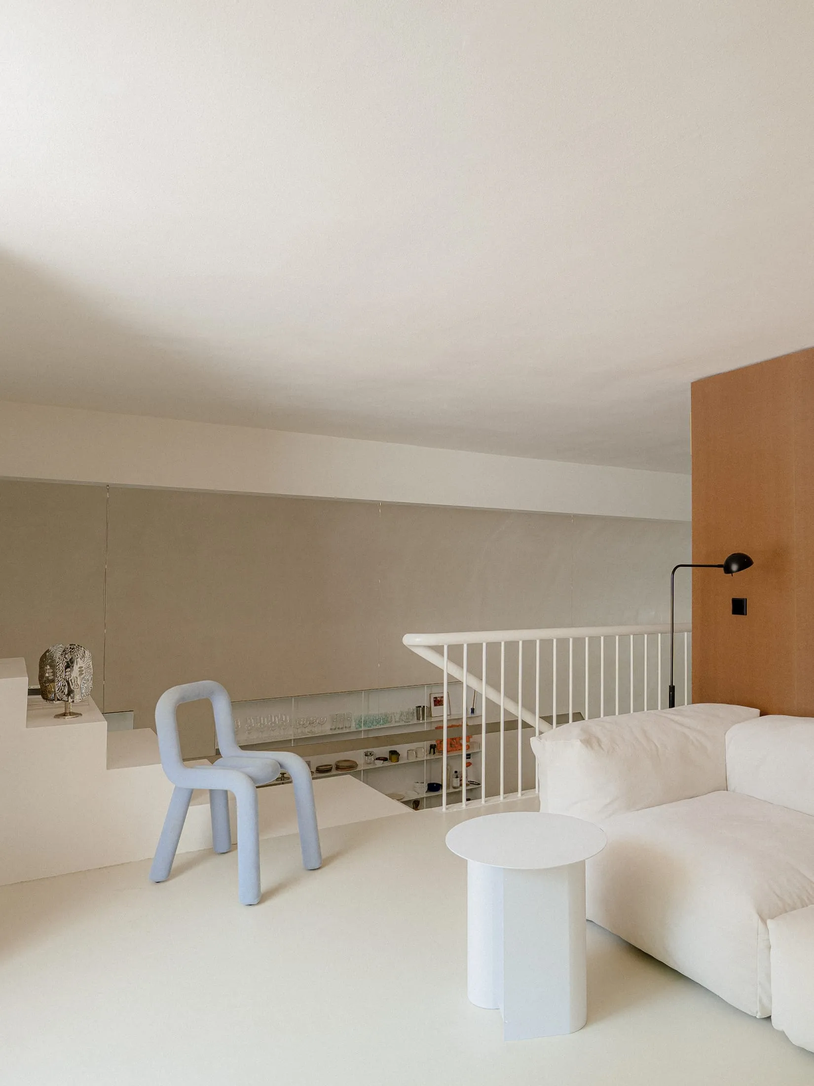 Open living area with a white couch, two chairs, a dining table, and scattered bottles, set against a clean and minimalist background