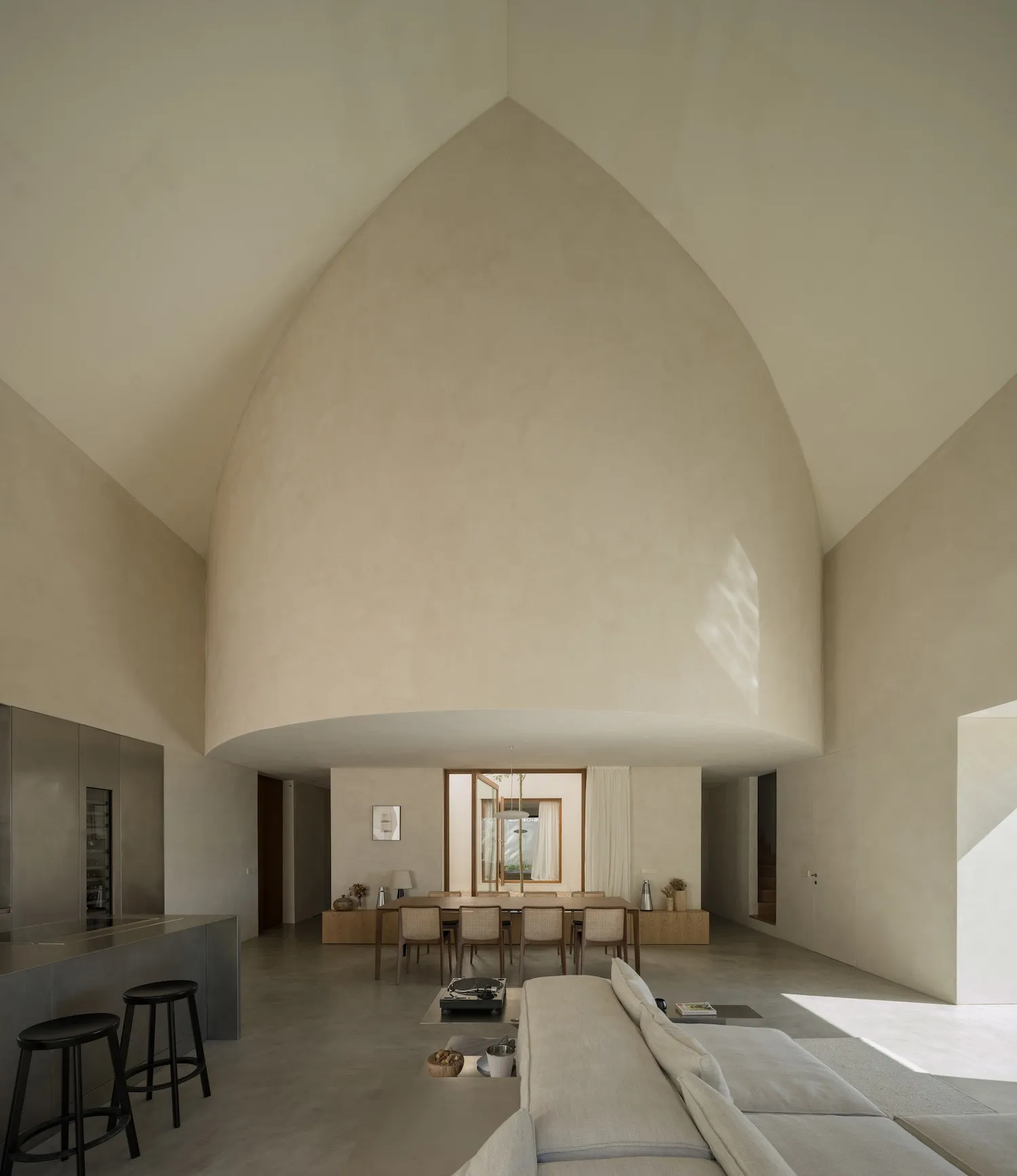 Open living space with cathedral ceiling, two couches, three chairs, and natural light from a window