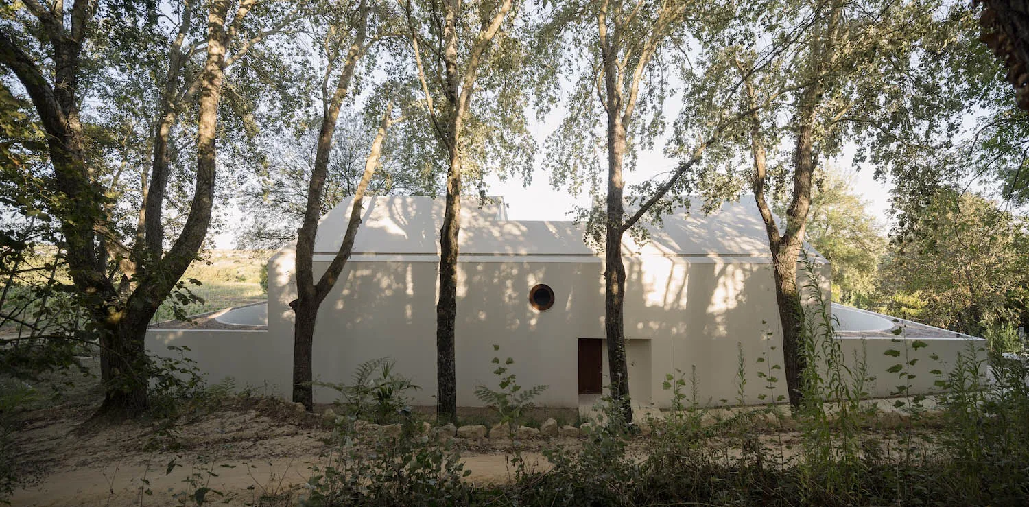 一座白色建築物的渲染圖，配有圓形窗戶，周圍環繞樹木，位於郊區或半鄉村地區