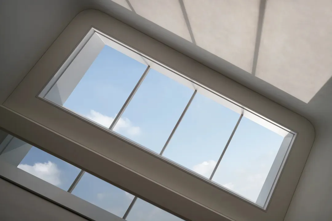 An empty white room with sunlight streaming through a two-paned window, creating a calm and serene atmosphere