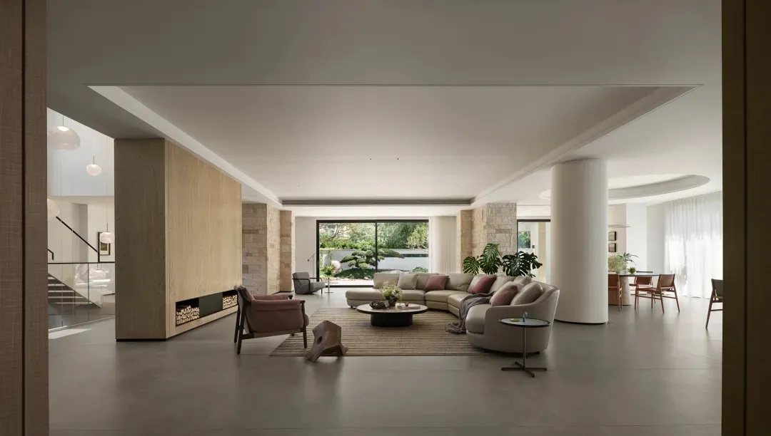 Bright and inviting living area with white interior, two couches, a chair, dining table, and potted plants