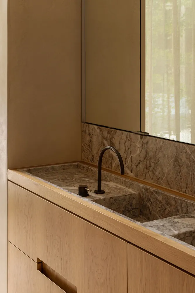 Bathroom with a marble sink, faucet, and two bottles, conveying luxury and elegance
